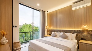 A modern bedroom with a large bed, wooden headboard, and a view of greenery through a sliding door.