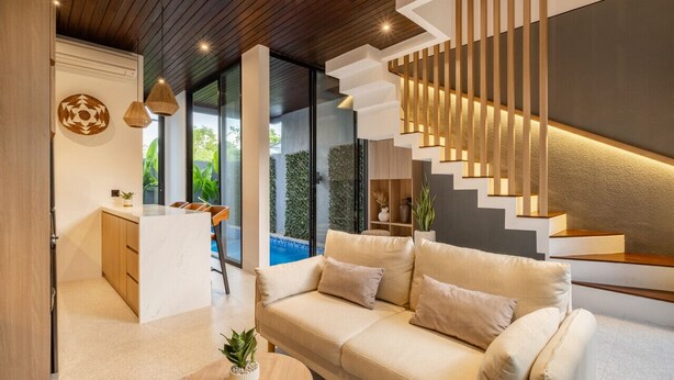 A modern living room with a sofa, a coffee table, and a staircase with integrated lighting.