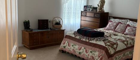 A bedroom with a bed, dresser, and a statue on the dresser.
