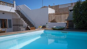 A swimming pool with a clear blue water surface, surrounded by a white building with a staircase leading to a balcony. - Nice house with 3 bedrooms, barbecue and private pool (Alcúdia)