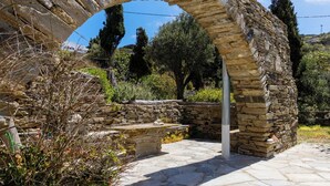 Un antiguo arco de piedra en un jardín, con muros de piedra y un banco de piedra.