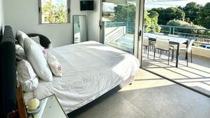 Une chambre moderne avec un grand lit, une télévision et un balcon équipé d’une table et de chaises.