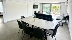 Un espace repas moderne avec une grande table, six chaises et un téléviseur fixé au mur.