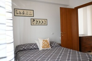 Une chambre à coucher avec un lit, une armoire en bois et deux tableaux encadrés accrochés au mur.