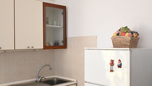 Eine Küche mit Spüle, Schränken, einem Kühlschrank und einer Obstschale.