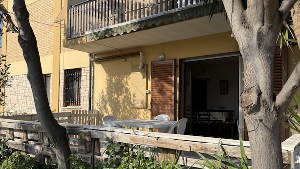 Ein Gebäude mit Balkon, Holzzaun und Tisch mit Stühlen.