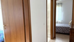 Ein Zimmer mit einem Bett, einer Tür und Blick auf ein weiteres Zimmer.