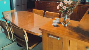 Une cuisine aux murs de couleur turquoise, avec des meubles en bois, un réfrigérateur en acier inoxydable, une table à manger avec des chaises et un vase rempli de fleurs posé sur la table.