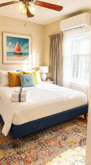 A bedroom with a bed, a ceiling fan, an air conditioning unit, a painting, a window with curtains, and a floral carpet. - King Bed 1BD 8 min to Downtown & Pier Pet-friendly (St. Petersburg)