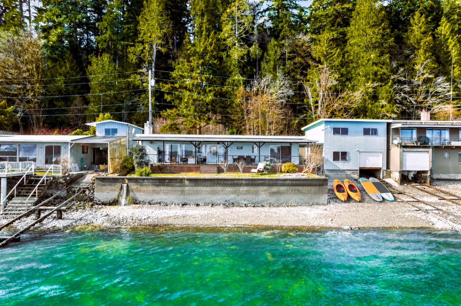 Propiedad frente al agua con varios edificios, un muelle y kayaks.