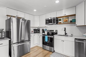 A modern kitchen with stainless steel appliances, white cabinetry, and a built-in oven. - Hood Canal Pearl - Waterfront, Hot tub, canal views (Shelton)
