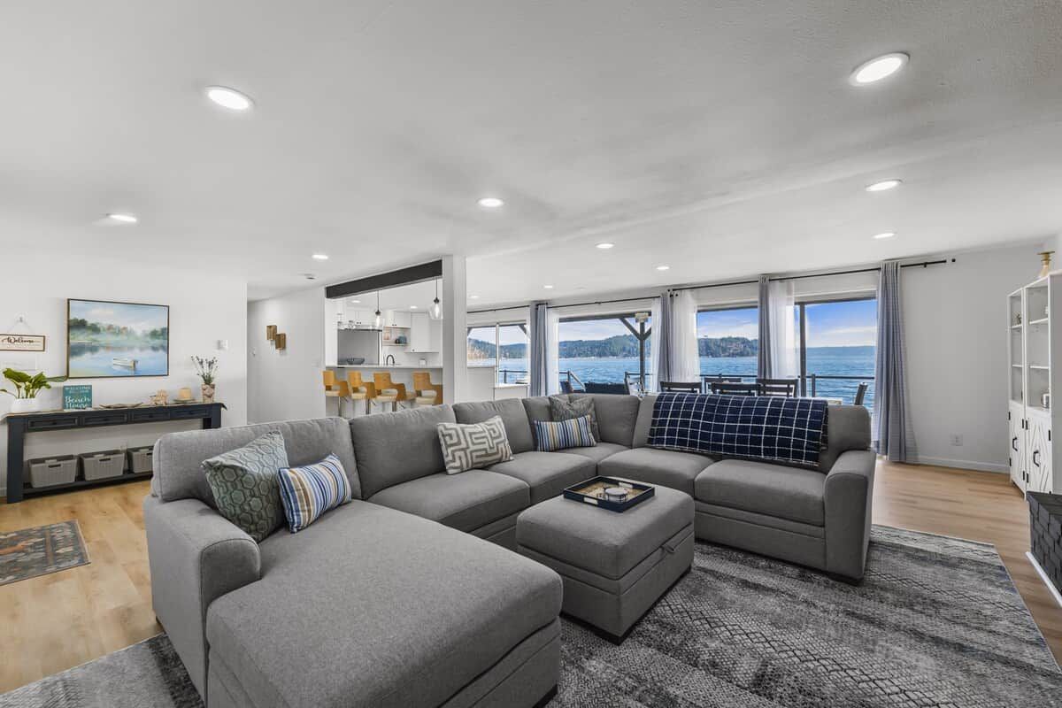 Una sala moderna con un sofá seccional grande, un comedor y vista al mar.