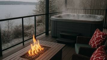 Una terraza con jacuzzi, una chimenea exterior y mobiliario para sentarse al aire libre.