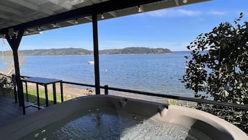 A hot tub with a view of a lake and distant land.