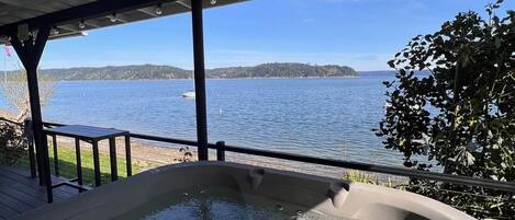 A hot tub with a view of a lake and distant land.