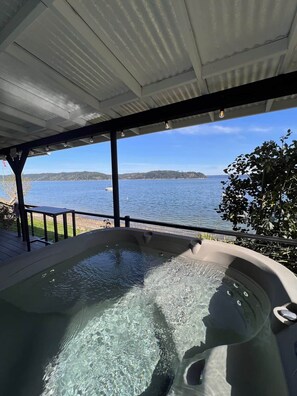 Un jacuzzi con vistas a un lago y terreno lejano.