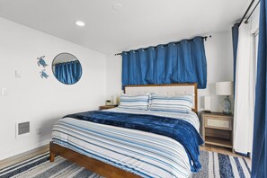 A bedroom with a bed, a nightstand, a lamp, a mirror, and a window with curtains. - Hood Canal Pearl - Waterfront, Hot tub, canal views (Shelton)