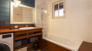 Une salle de bain avec un meuble-lavabo en bois, un évier, un miroir, une douche et une fenêtre.