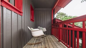 Une terrasse en bois avec deux chaises à bascule blanches et une rambarde rouge.