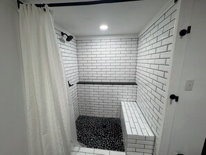 A bathroom with white tiled walls and a black and white patterned floor.