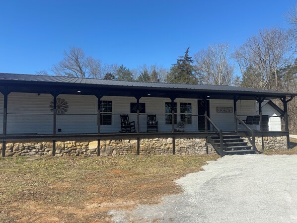 A historic building with a covered porch, stone foundation, and a sign reading "The Old Post Office."