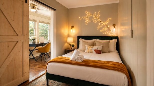 Une chambre à coucher comprenant un lit, un bureau, une chaise, une lampe et un luminaire fixé au mur.