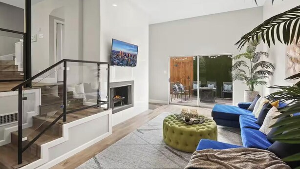 Ein modernes Wohnzimmer mit Treppe, Kamin, großem Fenster und einem blauen Sofa.