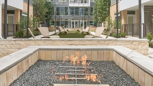 Een binnentuin met een vuurkorf, lounge stoelen en een zwembad.