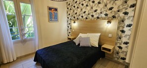 Een slaapkamer met een bed, een nachtkastje, een houten hoofdbord en een poster aan de muur.