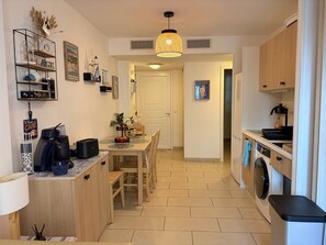 Une cuisine compacte comprenant un coin repas, un lave-linge et une machine à café.