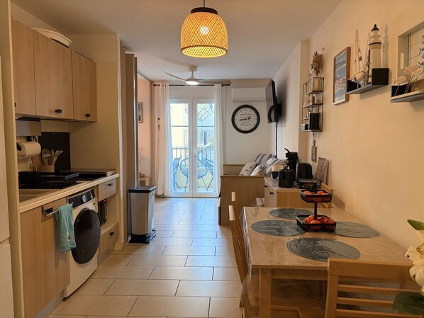 Une cuisine équipée d’un lave-linge, d’une table à manger avec des sets de table et d’un ventilateur de plafond.