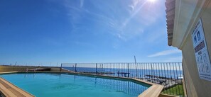 Ein Pool mit Meerblick, einem Zaun und einem Schild mit Text.