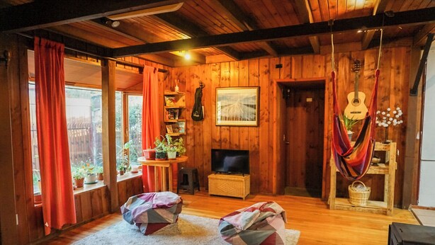 Accogliente interno di una baita in legno con camino, una chitarra e un'amaca.