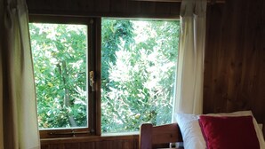 Una stanza piccola e accogliente con un letto di legno, un comodino e una finestra con tende.