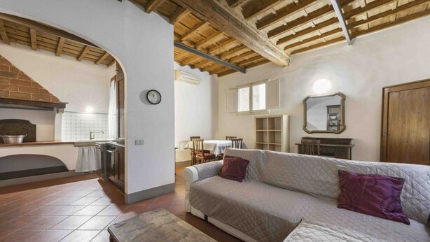 A cozy living room with a sofa, a wooden table, a fireplace, and a kitchen area. - Classic Florence A By MMega (Firenze)