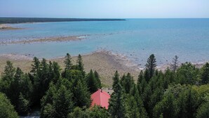 Blick auf die Küste mit Strand, bewaldetem Gebiet und einem Gebäude mit rotem Dach.