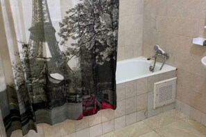 Bathroom features a shower curtain with a unique Eiffel Tower design, a bathtub, and a small sink.