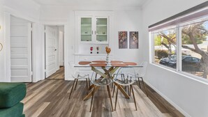 Una cocina moderna con una mesa de comedor de vidrio, armarios blancos y vistas al exterior.
