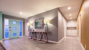 A hallway with a reception desk, two lamps, a mirror, and a door with frosted glass panels. - 4bd, Charming Mid-Century Home! 1.4mi to Convention Center, Mins to Strip! POOL! (Las Vegas)