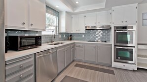 A modern kitchen with white cabinets, stainless steel appliances, and a tiled backsplash. - 4bd, Charming Mid-Century Home! 1.4mi to Convention Center, Mins to Strip! POOL! (Las Vegas)