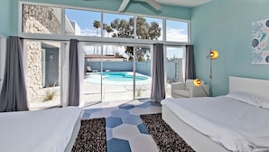 A bedroom with two beds, a ceiling fan, a pool view, and a stone wall. - 4bd, Charming Mid-Century Home! 1.4mi to Convention Center, Mins to Strip! POOL! (Las Vegas)