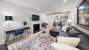 A modern living room with a fireplace, a TV, a sofa, and a desk with a chair.