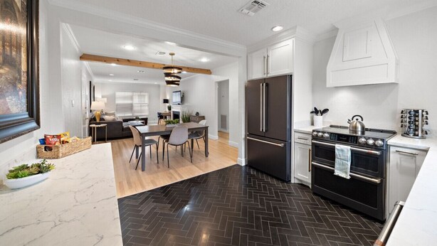A modern kitchen with a central island, a built-in oven, and a refrigerator.