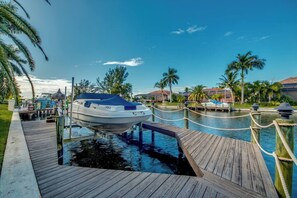 A boat docked at a marina with a wooden deck and a clear blue sky. - Palm Palace: Gulf Access Villa, Heated Pool & Spa, Sunsets (Cape Coral)