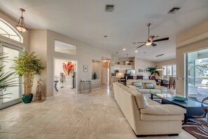 A spacious living area with a large sofa, a dining table, and a kitchen in the background. - Palm Palace: Gulf Access Villa, Heated Pool & Spa, Sunsets (Cape Coral)