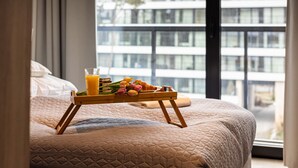 Un lit avec une couverture matelassée, un plateau avec du jus d’orange et des tulipes.