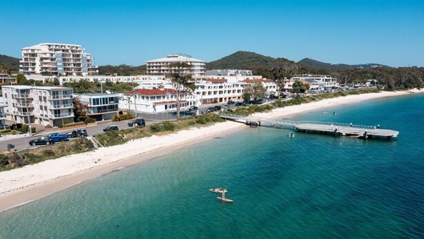 A coastal area with buildings, a beach, and a pier.