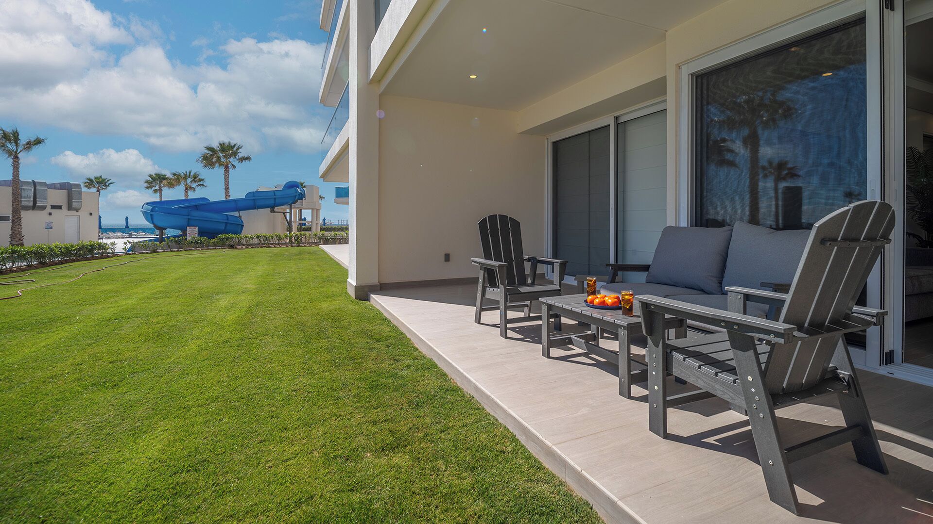 Eine Terrasse mit Sitzgelegenheiten im Freien, einer Wasserrutsche und Blick aufs Meer.