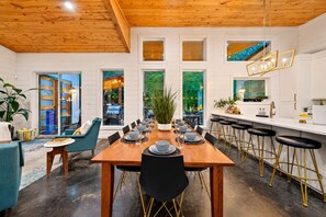 A modern dining area with a wooden table set for six, surrounded by bar stools. - 1-Story Stay | Hot Tub, PingPong, Arcade & Playset (Broken Bow)