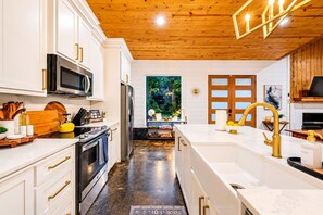 A modern kitchen with white cabinetry, stainless steel appliances, and a wooden ceiling. - 1-Story Stay | Hot Tub, PingPong, Arcade & Playset (Broken Bow)
